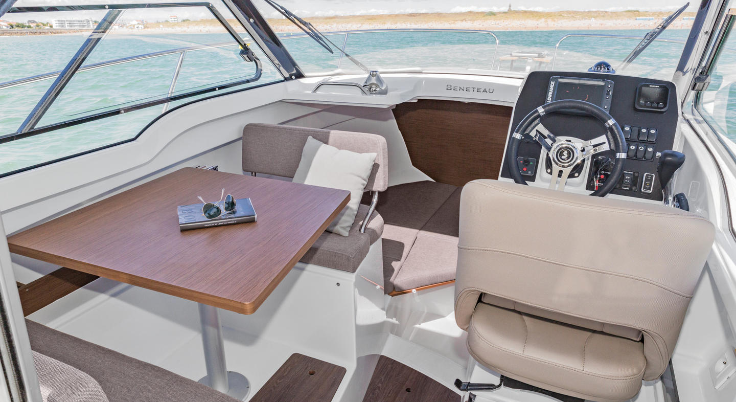 Photo du poste de pilotage de l'Antares 7 OB. On retrouve le cockpit et une deux banquettes face à face à côté de ce dernier. Les nombreuses vitres et ventilations de l'Antares 7 OB permettent une vision globale et une aération optimale.