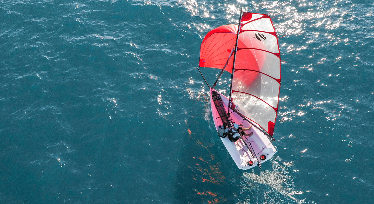 Photo aérienne du voilier First 14 SE. Le First 14 SE navigue avec 2 personnes à son bord. La carène moderne et large du bateau permet une véritable stabilité.