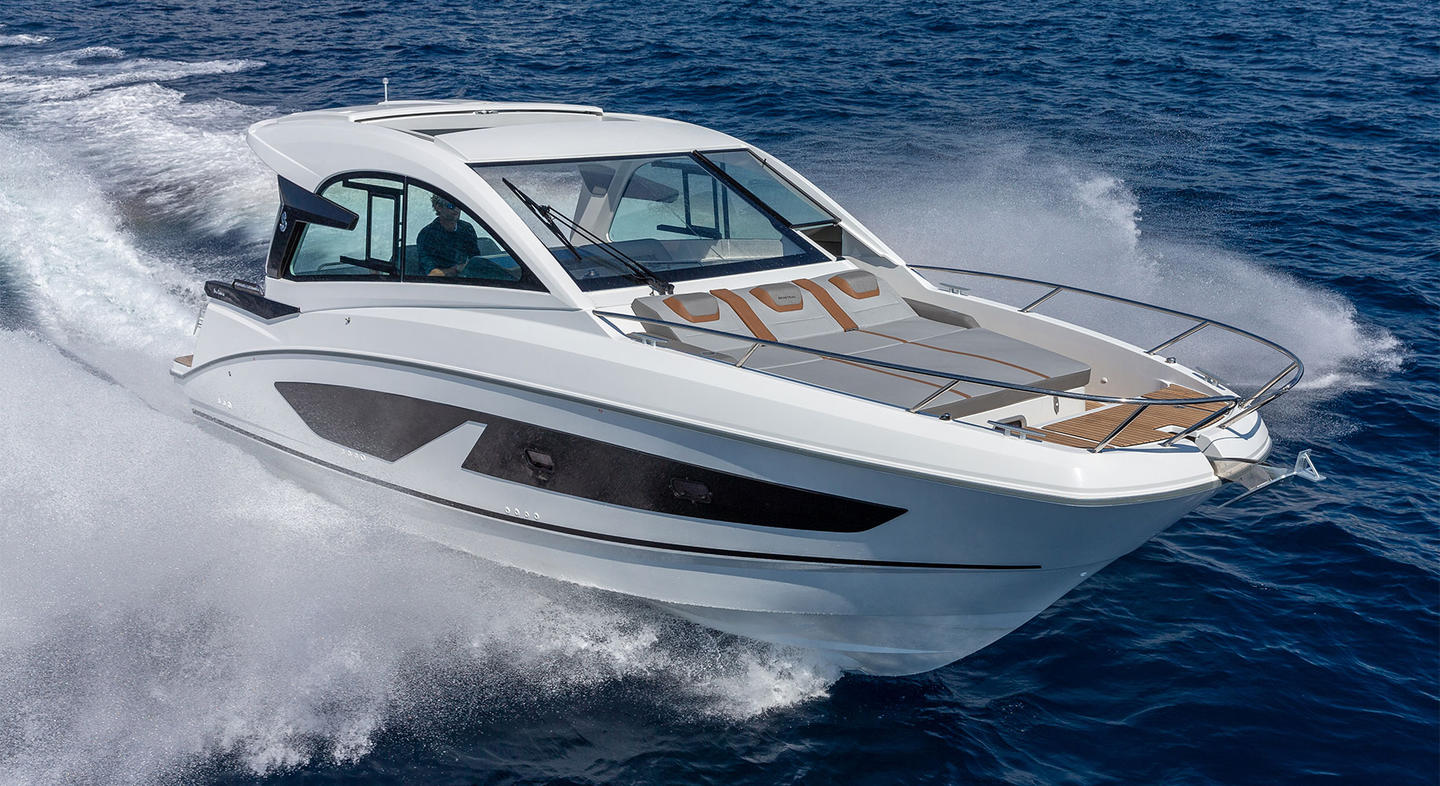 Vue du Gran Turismo 32 naviguant sur l'eau. Le bateau est blanc avec des lignes harmonieuses et modernes. Il possède à l'avant un espace pour prendre le soleil.